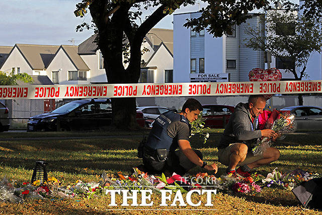 경찰들이 17일 뉴질랜드 크라이스트처치의 마스지드 알 노어 모스크 앞에서 꽃을 줍고 있다. 이번 총격 테러로 사망자 수가 50명으로 늘었다. /크라이스트처치(뉴질랜드)=AP.뉴시스
