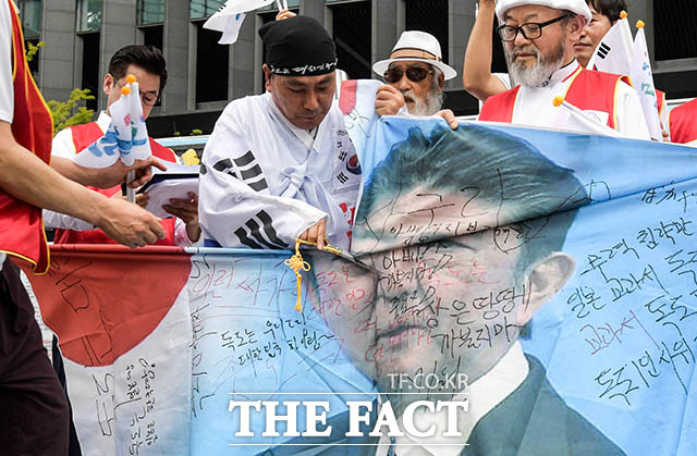 잘려지는 아베 신조 총리의 얼굴 지난 23일 옛 일본대사관 앞에서 열린 일본정부 규탄대회에서 한 시민이 아베 총리의 얼굴이 그려진 현수막을 가위로 찢고 있다.