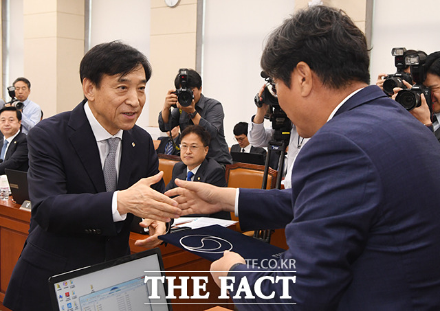 이춘석 위원장에게 증인선서문을 전달한 뒤 악수하는 이주열 한국은행 총재(왼쪽)
