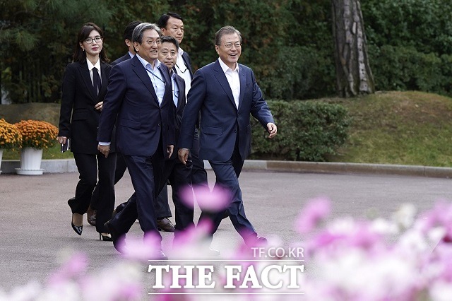 문재인 대통령이 25일 청와대 녹지원에서 열린 출입기자단 초청행사에 참모진과 입장하고 있다. /청와대 제공