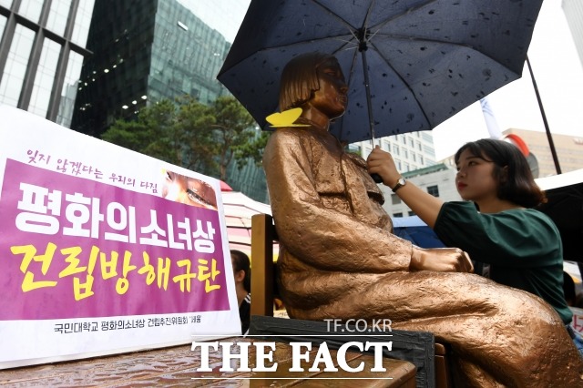 제 1397차 일본군 성노예제 문제 해결을 위한 정기 수요집회가 7월 24일 오후 서울 종로구 옛 일본대사관 앞에서 열린 가운데 한 참가자가 소녀상에게 우산을 씌워주고 있다. /남용희 기자