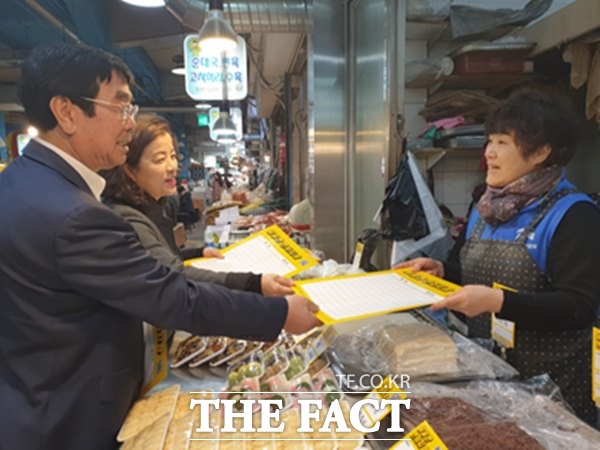 연서시장의 변세근 상인회 회장과 이인선 특성화첫걸음시장 육성단장이 스마트상점화를 위한 가격표시제 제작물을 시장상인들에게 배포하고 있다./연서시장 제공