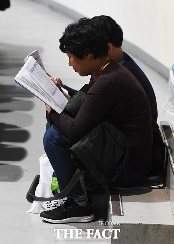 5일 오후 서울 중구 장충체육관에서 열린 종로학원, 2020 정시지원전략 설명회에서 한 학부모가 계단에 앉은 채 입시 자료를 보고 있다. /이동률 기자