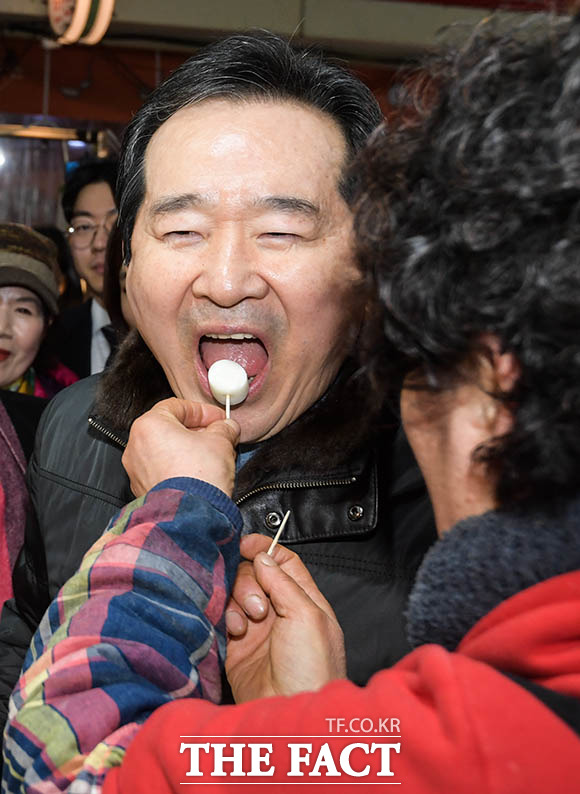 정세균 국무총리가 설 연휴를 일주일 앞둔 18일 오후 물가를 점검하기 위해 서울 중랑구 망우동 우림시장을 찾은 가운데 한 가게에서 떡을 시식하고 있다. /김세정 기자