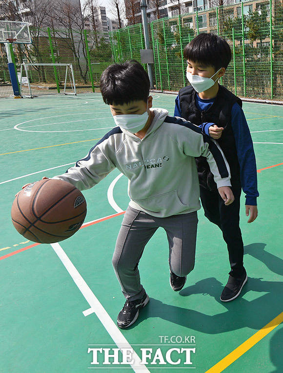 연기된 방학에 학교 운동장에서 마스크를 쓰고 농구를 하는 어린이들