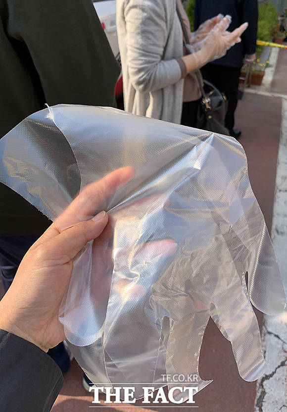 손 소독제를 바르고 일회용 비닐장갑을 배급 받는 유권자들