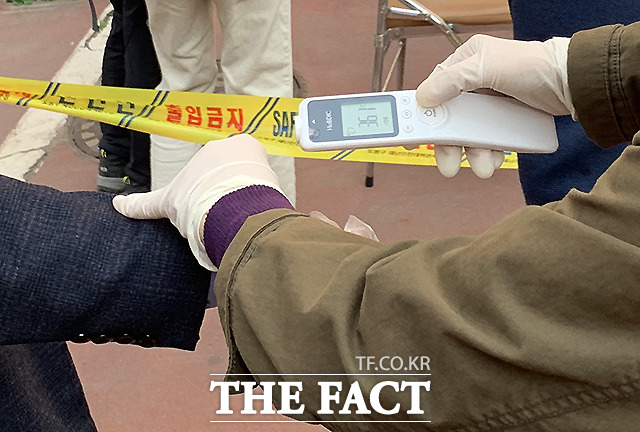 선관위 관계자가 유권자들의 체온을 측정하고 있다.