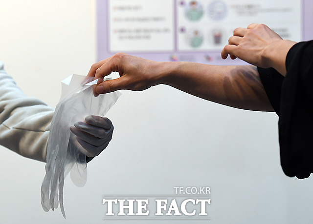 제 21대 국회의원 선거일인 15일 오전 서울 종로구 동성고등학교에 마련된 혜화동 제3투표소에서 한 유권자가 코로나19 방역을 위해 일회용 비닐장갑을 건네받고 있다./이새롬 기자