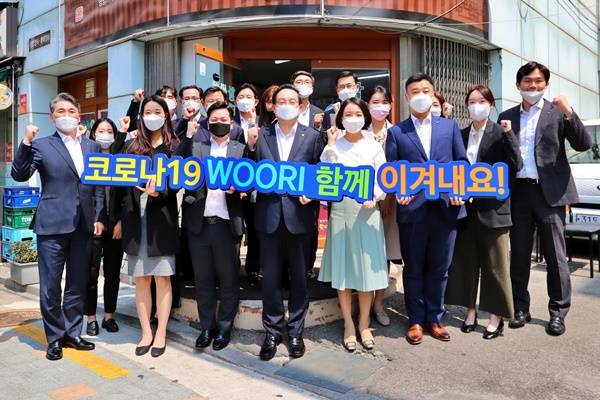 우리금융그룹은 코로나19로 어려움을 겪고 있는 본점 인근 음식점을 돕기 위해 착한소비운동에 동참한다. 손태승(가운데) 우리금융그룹 회장이 16일 본점 인근 식당에서 임직원들과 점심식사 후 코로나19로 어려움을 겪고있는 이들에게 응원의 메시지를 보내고 있다. /우리금융그룹 제공