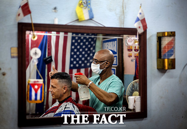 침묵 손질 25일(현지시간) 쿠바 수도 아바나의 한 이발소에서 마스크를 쓴 이발사가 손님 머리카락을 매만지고 있다. /아바나=AP.뉴시스