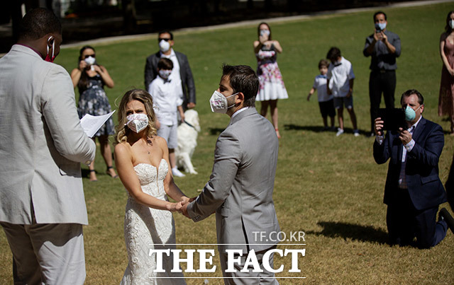색다른 혼인서약 27일(현지시간) 미 텍사스주 휴스턴의 하인스 워터폴 공원에서 코로나19 예방을 위해 마스크를 쓴 남녀가 결혼식을 올리고 있다. /휴스턴=AP.뉴시스