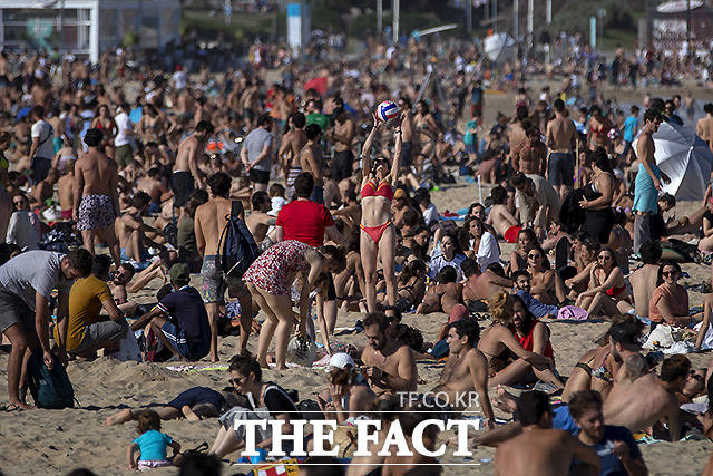 12일 (현지시간) 더워진 날씨에 스페인 바르셀로나의 한 해변을 찾은 시민들이 모여 일광욕을 즐기고 있다.
