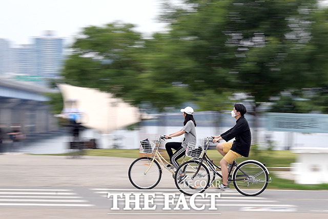 서울 낮 최고기온이 27도까지 오른 18일 오후 서울 영등포구 여의도 한강공원에서 한 커플이 더위를 피해 자전거를 타고 있다. /이선화 기자