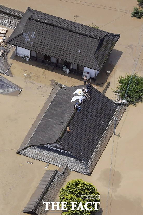 기록적 폭우에 일본 인명피해가 속출하고 있다. 4일 일본 규슈지역 구마모토현 히토요시에서 폭우로 가옥이 물에 잠기자 주민들이 지붕 위에 올라가 구조를 기다리고 있다. /AP, 뉴시스