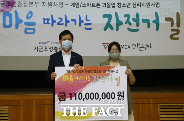 김광식 경륜경정관리본부장(왼쪽)이 25일 광명YMCA 강옥희 사무총장에게 게임/스마트폰 과몰입 청소년 심리지원사업 마음 따라가는 자전거 길에 지원금을 전달하고 있다./기금조성총괄본부 제공