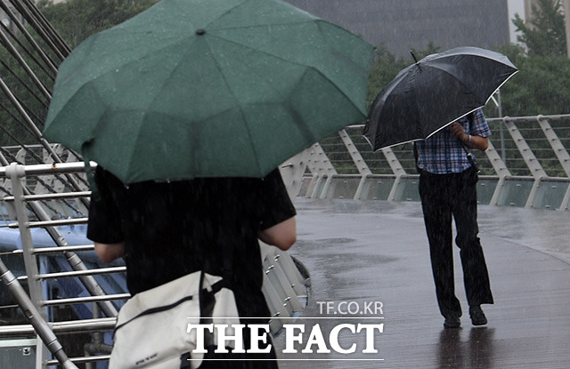 샛강생태공원인근을 지나는 시민들이 강풍을 동반한 폭우에 우산을 내려쓰고 있다.
