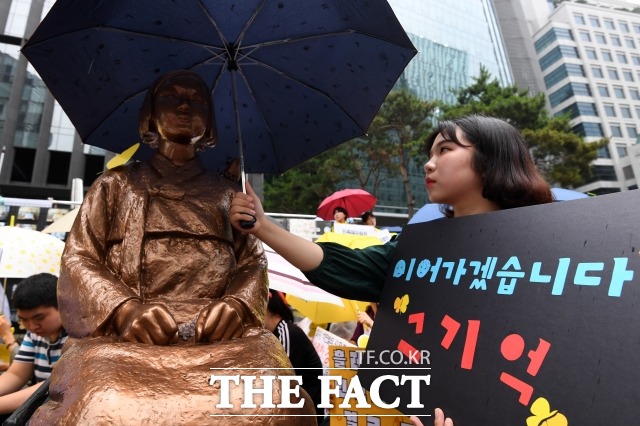 일본을 상대로 위안부 피해자들이 낸 손해배상 소송이 4년여 만에 마무리 절차를 밟는다. 사진은 지난해 7월 서울 종로구에서 열린 정기 수요집회에서 한 참가자가 소녀상에게 우산을 씌워주는 모습. /남용희 기자