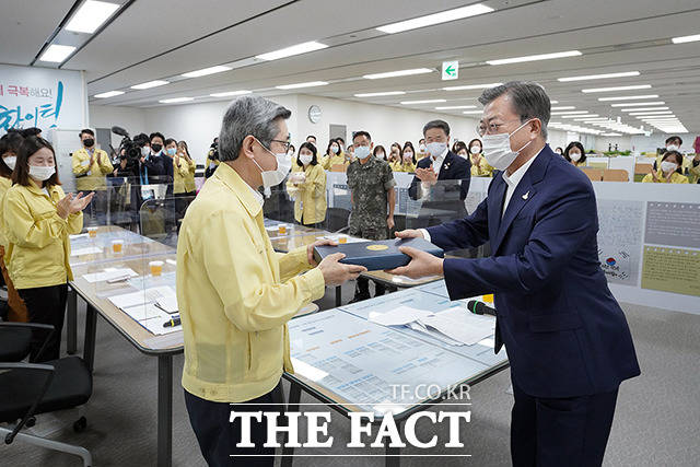 문재인 대통령이 11일 오전 세종특별자치시 정부세종청사 코로나19 중앙사고수습본부를 방문해 노홍인 중앙사고수습본부 총괄책임관(왼쪽)에게 격려 선물을 전달하고 있다. / 청와대 제공