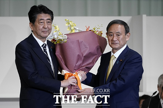 아베 신조 일본 총리(왼쪽)에게 꽃다발 선물 받는 스가 요시히데 자민당 신임 총재.