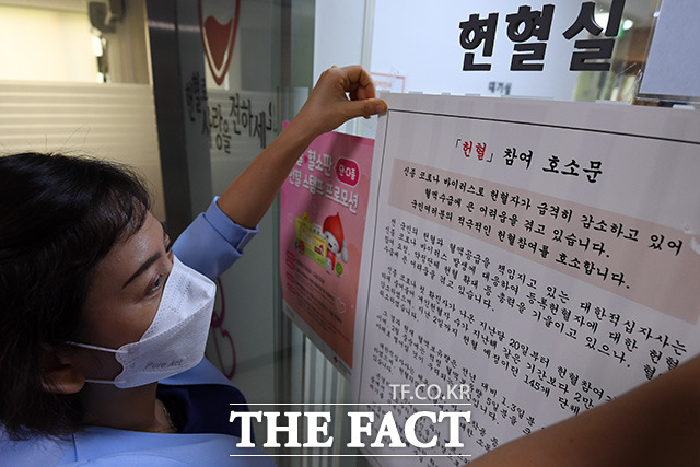 헌혈실 입구에 간호사가 헌혈 참여를 독려하는 헌혈 참여 호소문을 붙이고 있다.