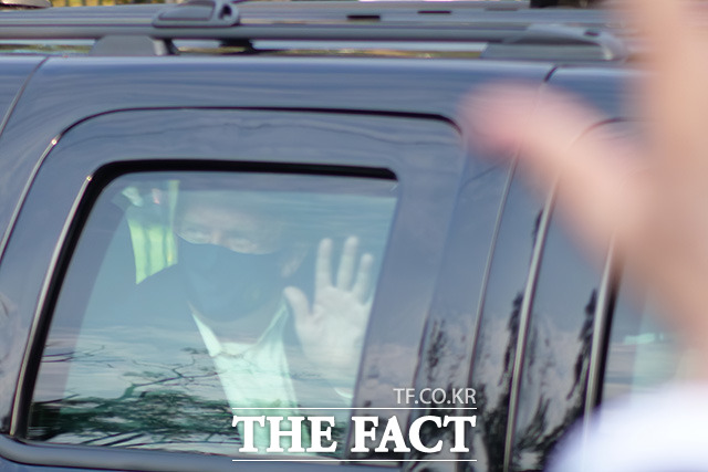 코로나로 입원 치료중인 도널드 트럼프 미국 대통령이 4일(현지시각) 경호원과 함께 차를 타고 자신이 입원한 월터 리드 군병원 바깥으로 외출해 손을 흔들고 있다./베데스다=AP.뉴시스