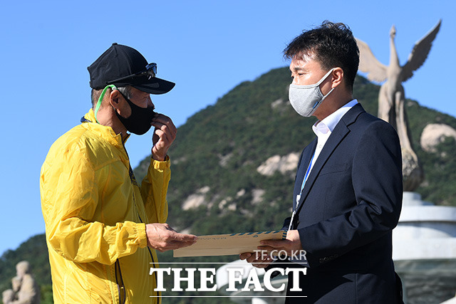 문재인 대통령이 북한군에 의해 피살된 해양수산부 공무원 이모(47)씨의 고교생 아들 편지에 답장을 보냈다. 피살 공무원 이 씨의 형 이래진씨(왼쪽)가 8일 청와대 분수대 앞에서 청와대 시민사회수석 비서관실 행정관에게 이 씨의 아들이 작성한 자필 편지를 전달하던 당시. /남용희 기자