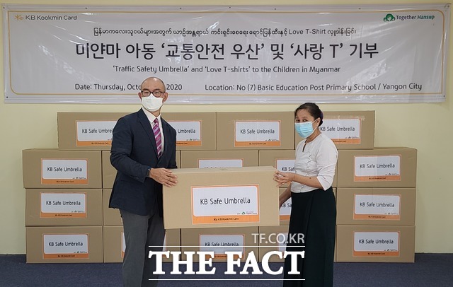 10월 22일 미얀마 양곤 7번 학교에서 열린 교통안전 우산과 사랑의 티셔츠 전달식에서 이익수 KB국민카드 미얀마 양곤 대표 사무소장(왼쪽)이 도 흘라라(DAW HLA HLA) 7번 학교 교무 교사에게 기부 물품을 전달하고 있다. /KB국민카드 제공