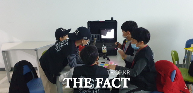 오는 21일까지 매주 토요일 열리는 떠나요 과학소풍 프로그램에서 지역 학생들이 적외선 수사 도구를 활용해 잉크가 쏟아져 보이지 않는 편지 내용을 확인 중이다./ 광주시 북구 제공