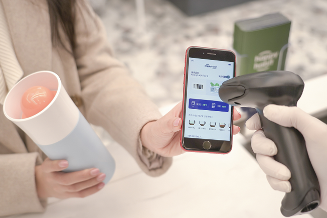 고객이 커피 매장에서 일회용 플라스틱컵 대신 텀블러를 이용하면서 해피 해빗 앱을 통해 환경 보호 기여도를 확인하고 있다. /SKT 제공
