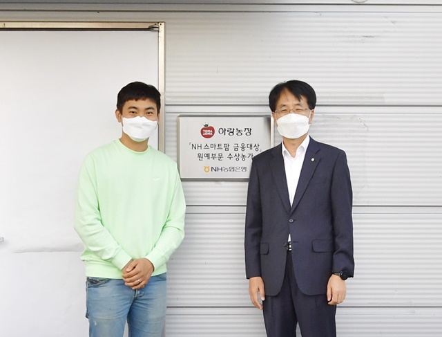 손병환 농협은행장(오른쪽)과 허정수 하랑농장 대표가 지난 12일 전북 김제시에 위치한 하랑농장에서 NH 스마트팜 금융대상 현판식을 진행하고 기념촬영을 하고 있다. /NH농협은행 제공