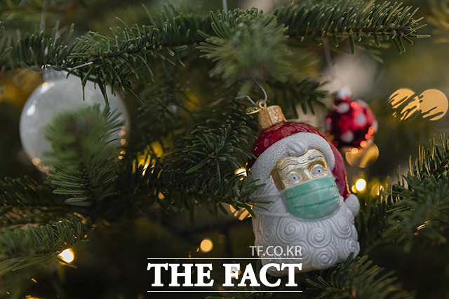 독일 크리스마스 트리엔 산타 모양의 장식이 마스크를 쓰고 있다.