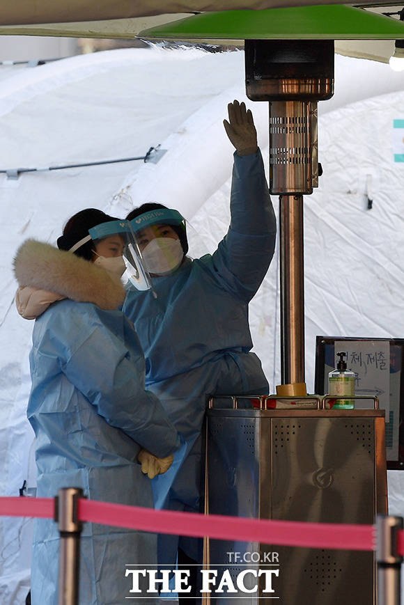 서울역에 마련된 임시 선별 검사소에서 의료진이 난로에 모여 몸을 녹이고 있다. /이선화