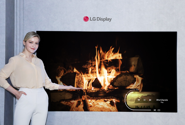 LG디스플레이 모델이 신규 OLED 소자가 적용된 77인치 차세대 OLED TV 패널을 소개하고 있다. /LG디스플레이 제공