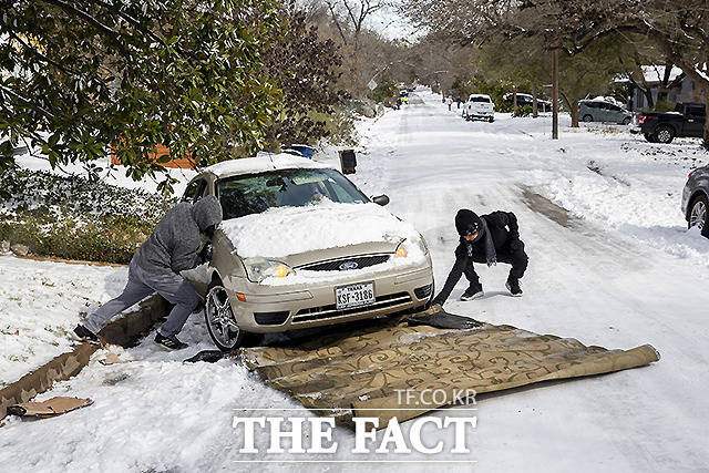 16일 텍사스 주 오스틴에서 주민들이 카펫을 깔고 차량을 밀어내고 있다.