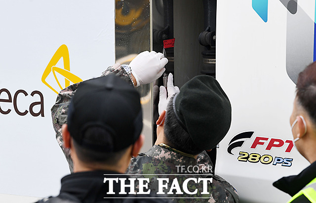 군 관계자가 도착한 백신 수송 차량에 붙은 봉인지를 제거하고 있다.
