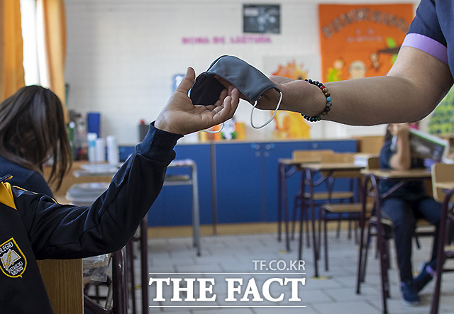 칠레 산티아고에서 대면 수업 첫 날인 1일 학생들에게 마스크를 나눠주고 있다.