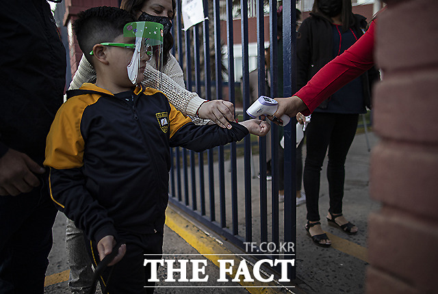칠레 산티아고의 한 어린이가 1일 (현지시간) 학교 정문에서 교실에 입실을 앞두고 체온을 측정하고 하고 있다. /산티아고=AP.뉴시스