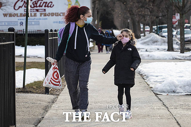 1일(현지시간) 시카고 로저스 파크 인근에서 한 여성이 아이의 등교를 도우며 마스크를 고쳐 주고 있다.