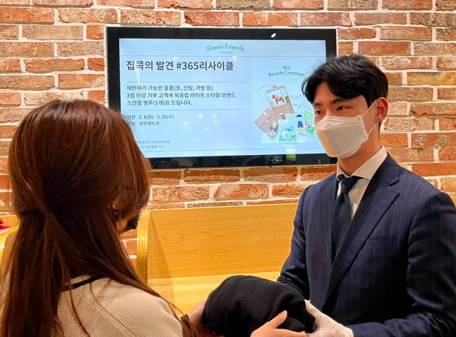 현대백화점이 365 리사이클 캠페인을 전 점포로 확대 운영한다. 사진은 현대백화점 직원이 친환경 캠페인 참여 고객으로부터 헌 옷을 수거받고 있는 모습. /현대백화점 제공