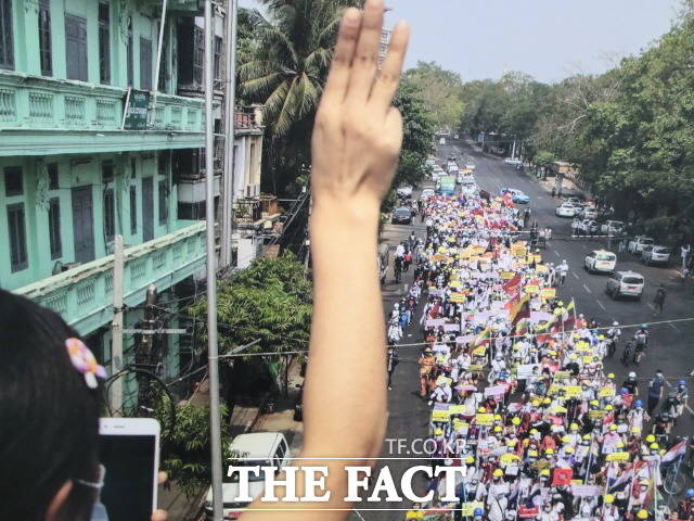 미얀마의 한 시민이 아파트 옥상에서 군부 쿠데타 규탄의 상징인 세 손가락을 세우고 거리의 시위대에 지지를 보내고 있다. /미얀마민주화응원 사진전 캡처