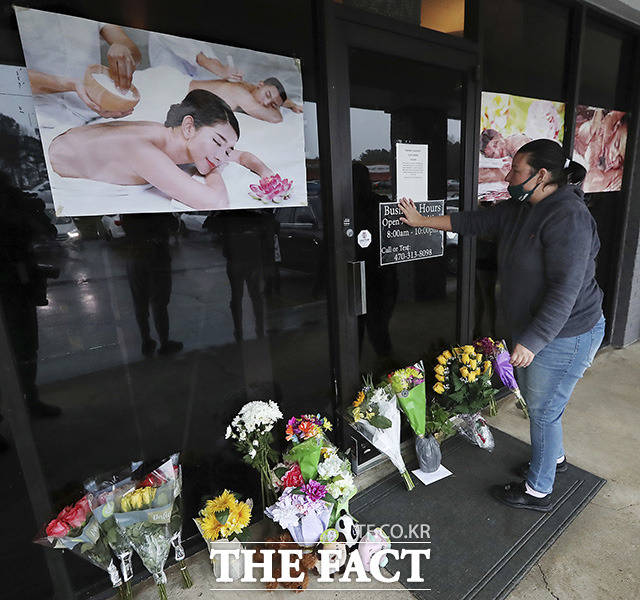 미 조지아주 애틀랜타 총격으로 4명이 숨진 애크워스의 영 아시안 마사지 숍 앞에서 한 여성이 꽃다발을 들고 희생자들을 애도하고 있다.