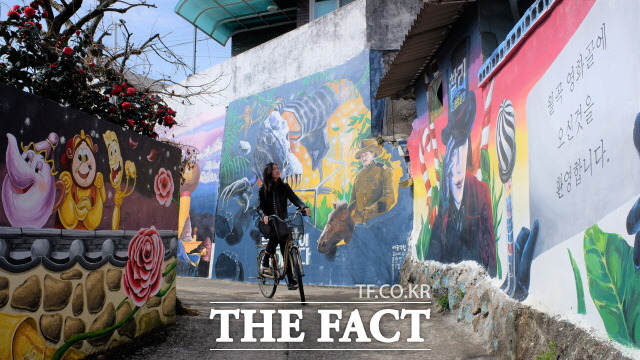 보성군 벌교읍 월곡 영화골 벽화마을을 찾은 관광객이 22일 자전거를 타고 벽화를 감상하고 있다. /보성군 제공