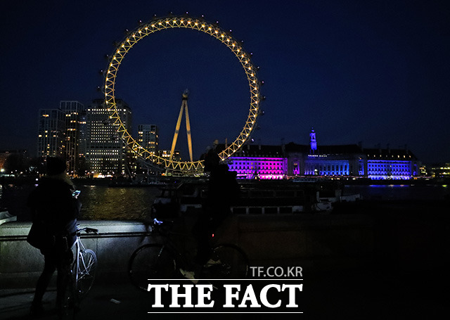 23일(현지시간) 영국 런던의 런던 아이가 코로나19 확산 방지를 위한 국가 봉쇄 1주년을 맞아 노란빛으로 물들어 있다. /런던=AP.뉴시스