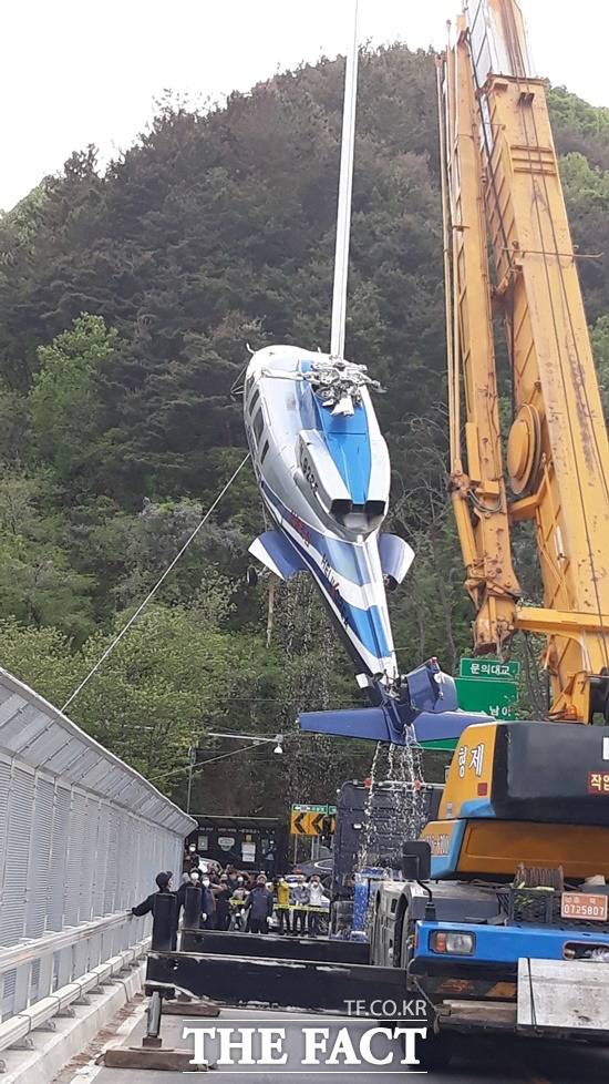 23일 오후 6시쯤 청주시 문의면 문의대교에서 지난 21일 오후 3시쯤 대청호에 추락한 충북도 소방헬기가 인양돼 크레인으로 트레일러로 옮겨지고 있다. / 김영재 기자