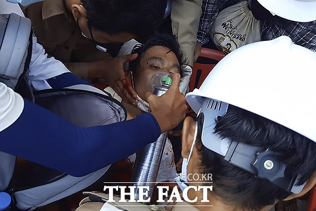 2월 28일 미얀마 다웨이의 한 거리에서 군경의 유혈 진압으로 다친 한 시위대 참가자가 산소마스크를 쓴 채 구급차를 기다리고 있다. /다웨이=AP.뉴시스