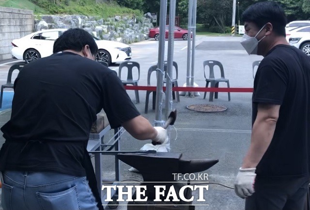 5일 오전 ‘웰컴 투 대장간’ 주말 체험을 위해 충북 보은 농경문화관을 찾은 시민(왼쪽)이 망치로 쇠를 두드리고 있다. 무형문화재 전수조교(오른쪽)가 시민을 보고있다. / 보은=전유진 기자