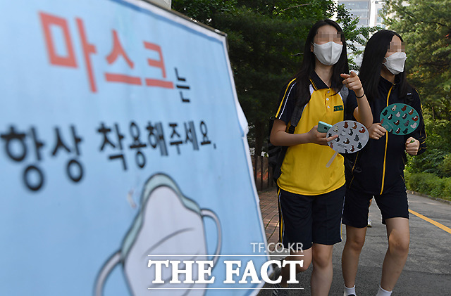 서울 강남구 언주중학교에서 등교하는 학생들 너머로 마스크 착용을 알리는 안내판이 보이고 있다.