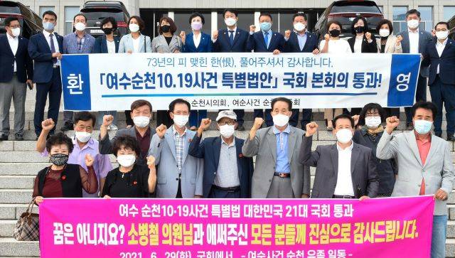 여순사건 유족들과 순천출신 시도의원들이 여순사건 특별법이 통과된 직후 국회의사당 앞에서 환영과 축하 메시지를 담은 펼침막을 들어보이고 있다. /순천시의회 제공