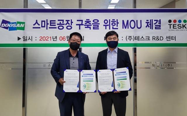 이용진 두산인프라코어 구매총괄 전무(오른쪽)와 황정상 테스크 대표가 스마트공장 구축 지원 양해각서를 체결한 후 기념사진을 촬영하고 있다. /두산인프라코어 제공