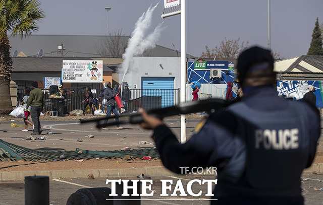 12일(현지시간) 남아프리카공화국 요하네스버그에서 시위대가 경찰을 향해 소화기를 뿌리고 있다./요하네스버그=AP.뉴시스